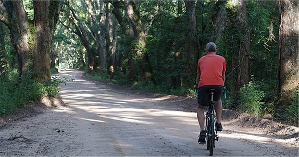 Man riding a bike on dirt road.