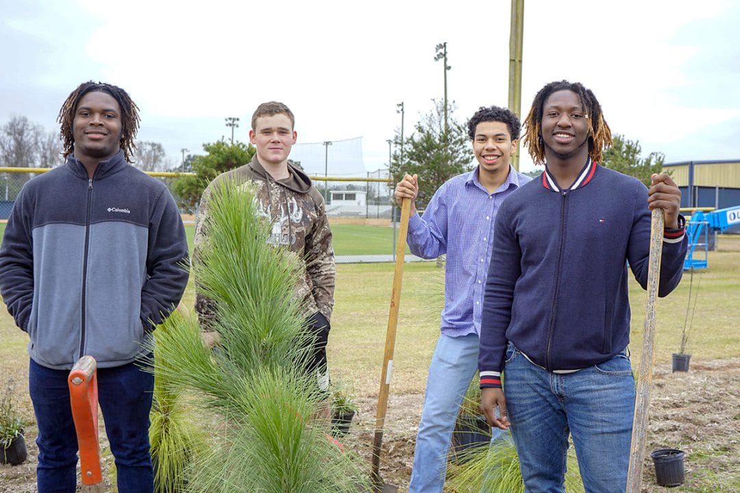Students express their satisfaction after the hard work of planting a few of the larger longleaf pines included for instant structure.