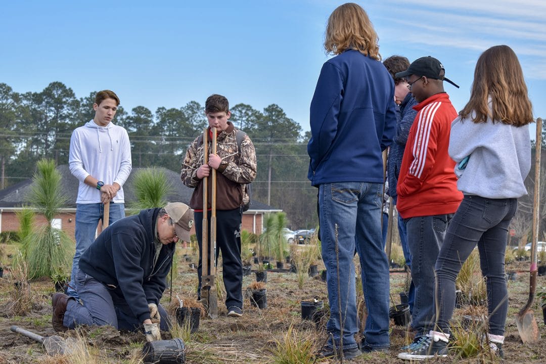 Brian Wiebler, Red Hills Outreach & Education Coordinator, demonstrates proper planting techniques to students.